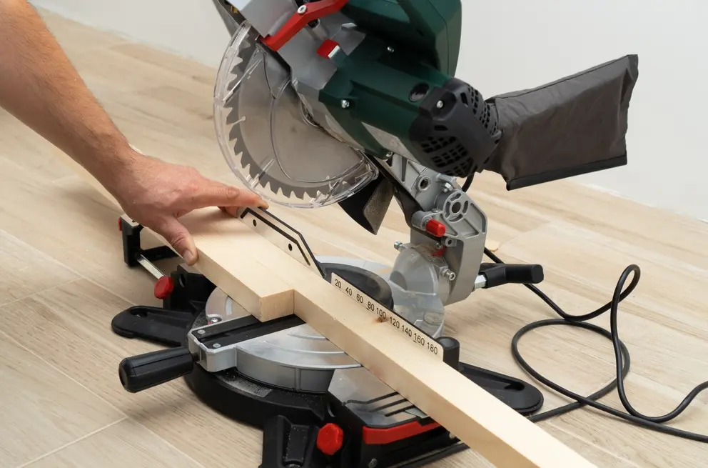 miter saw in hands of a handyman sawing wood parts